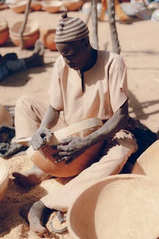 A skilled artisan working on calabash bowls in an African marketplace, showcasing traditional craftsmanship.