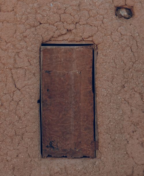 Free A wooden door set in a rustic mud brick wall, showing traditional construction techniques. Stock Photo