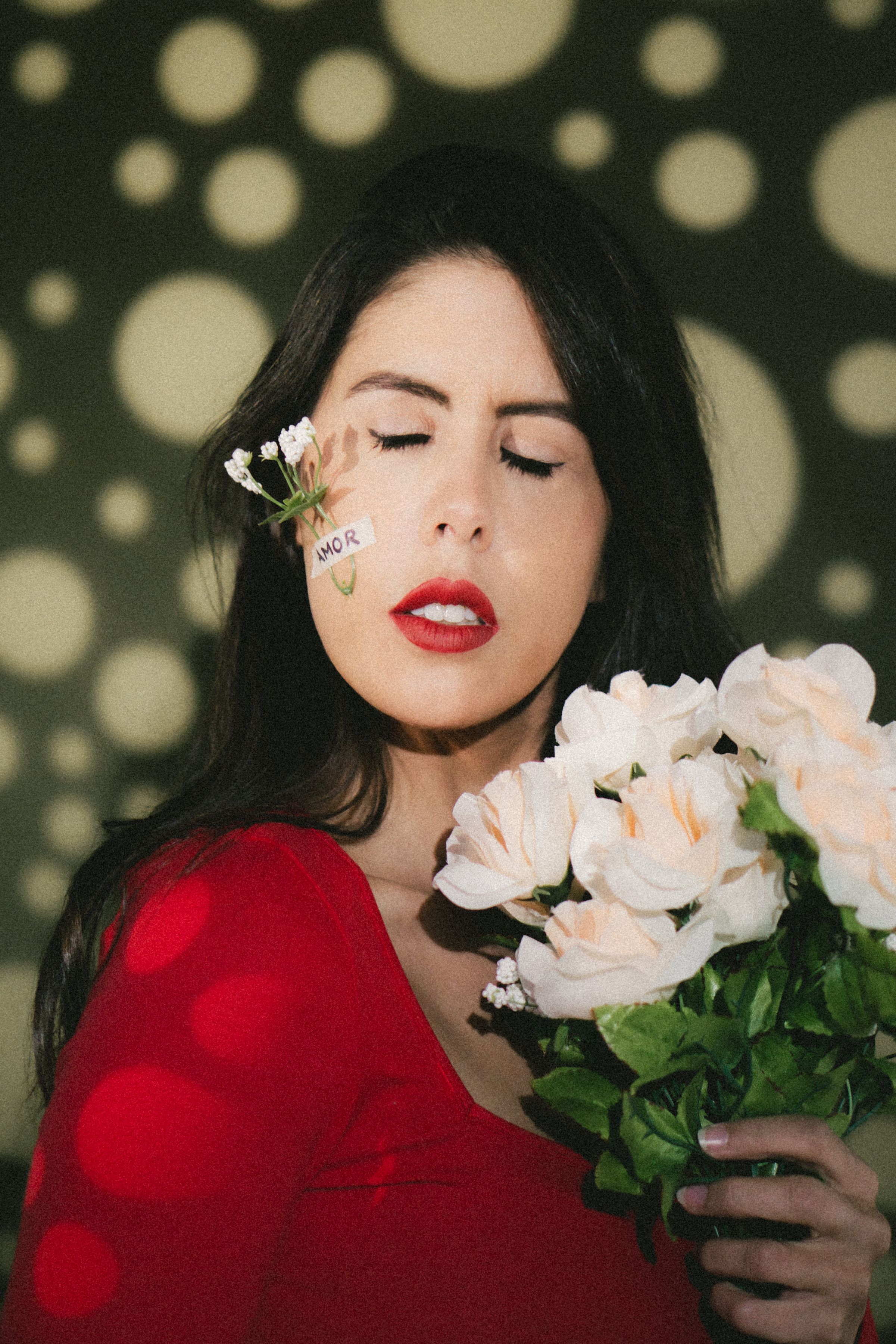 A woman holding flowers with artistic light patterns on her face, creating a dramatic visual effect.