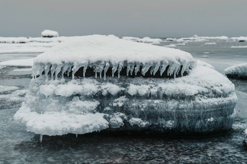 Free Serene winter scene featuring ice-covered rocks by the water's edge, capturing a magical atmosphere. Stock Photo