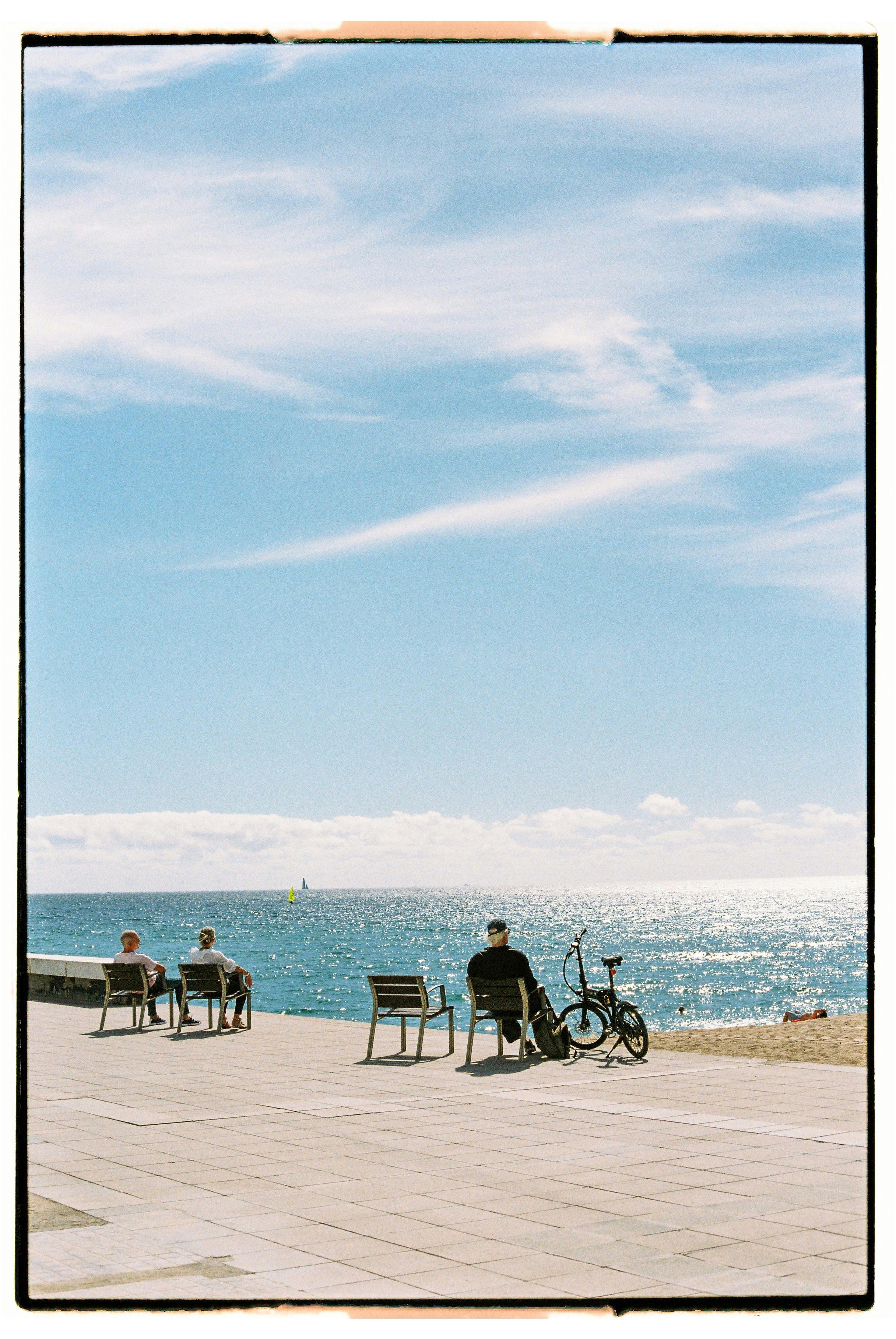 People relaxing by the sea on a sunny day with clear blue skies.