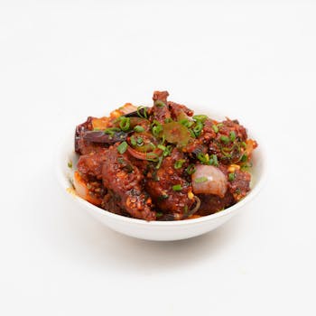 Delicious spicy Asian stir-fry topped with green onions in a white bowl.