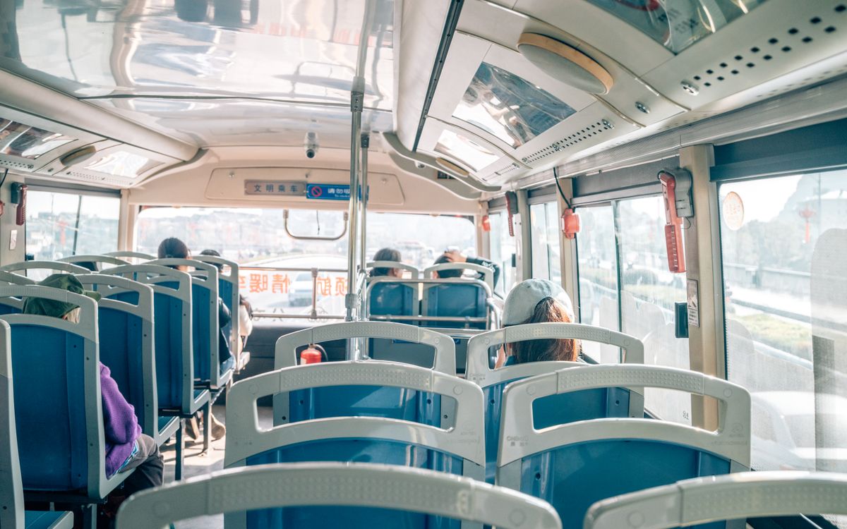 Bright interior of a public bus with passengers enjoying the sunny ride.