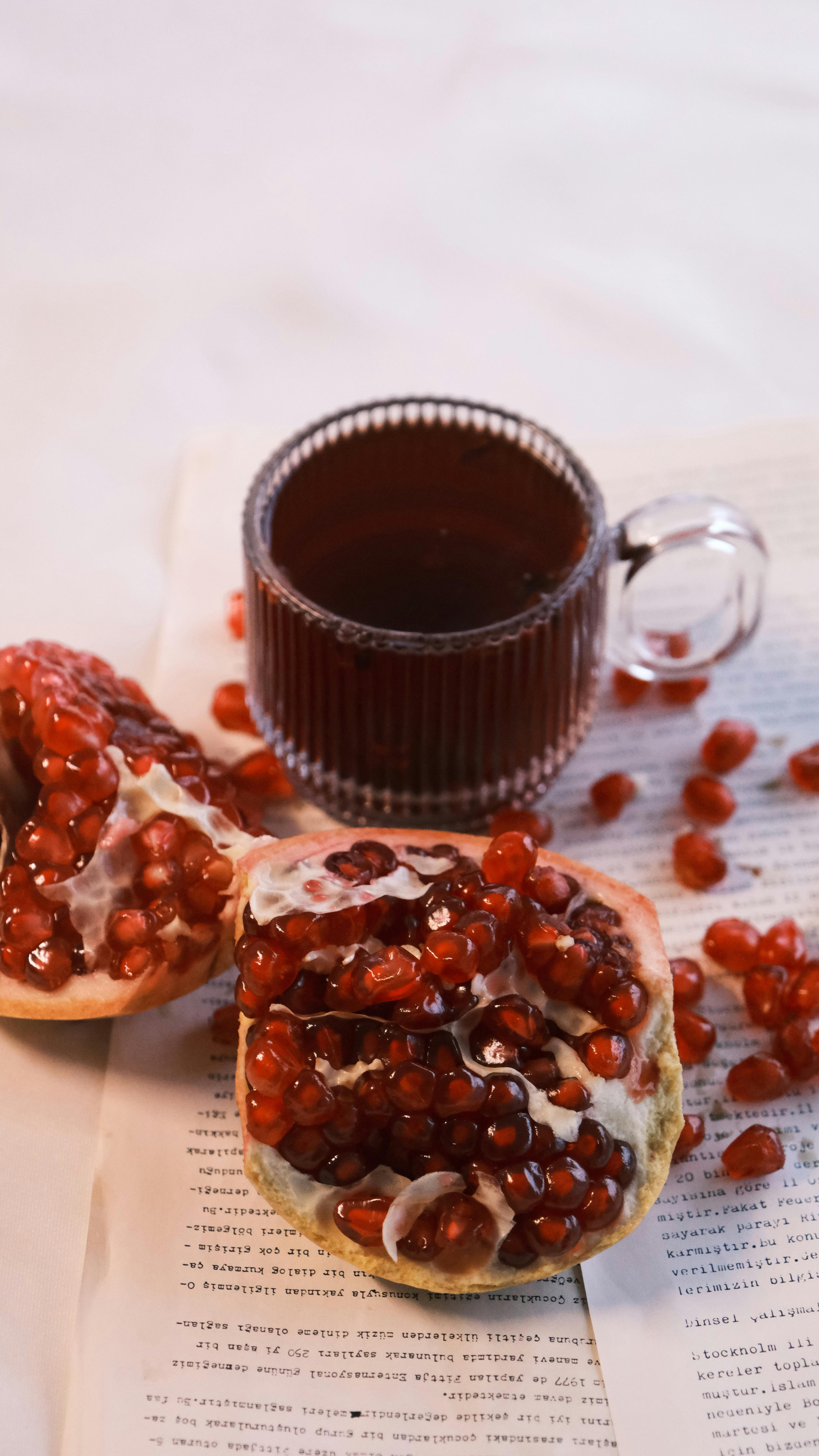 pomegranate seeds with tea on open book