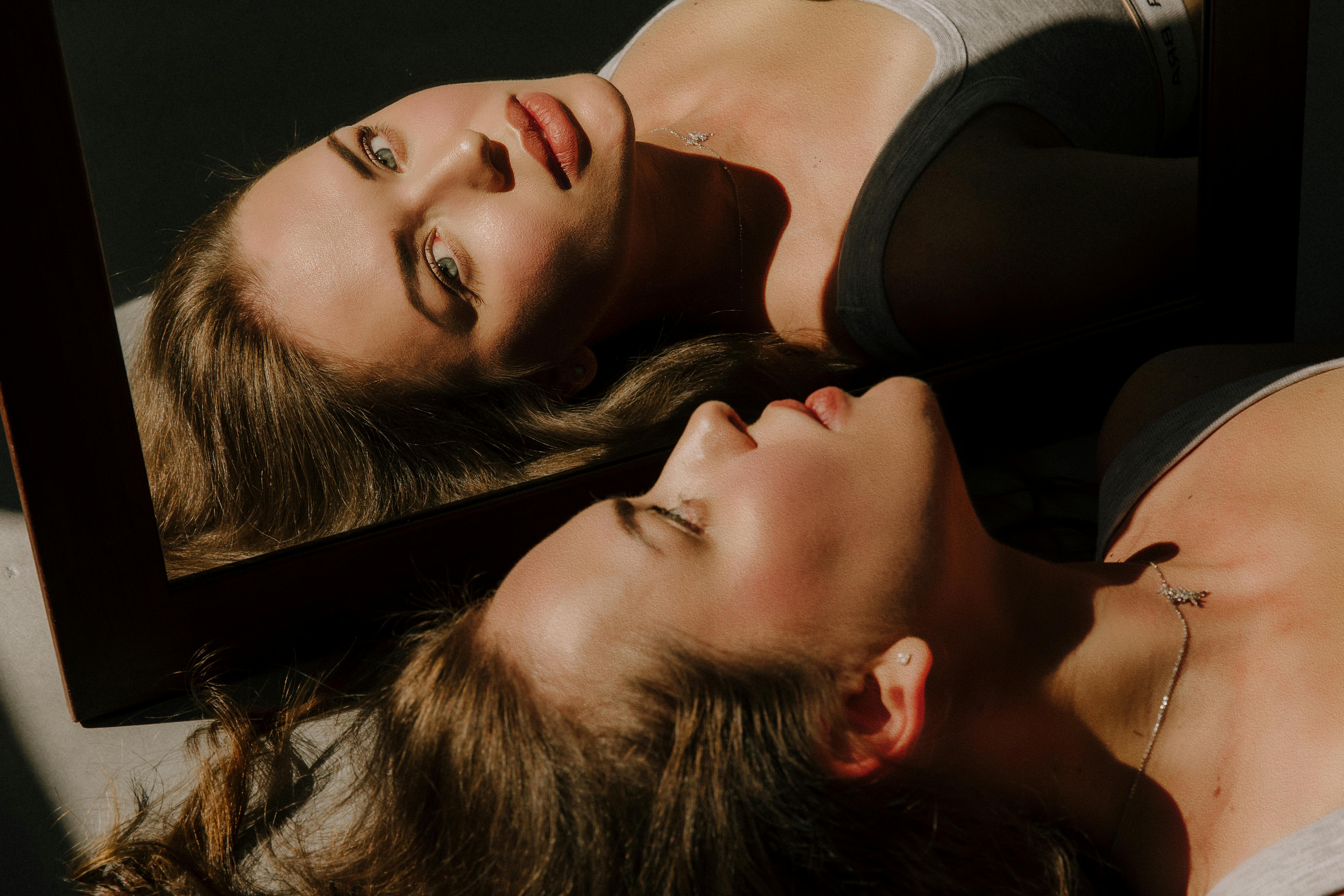 Elegant portrait of a woman with a mirror reflection, capturing serene beauty in soft lighting.