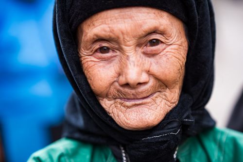 Free Close-up portrait of a senior woman with a warm smile, wearing a traditional headscarf. Stock Photo