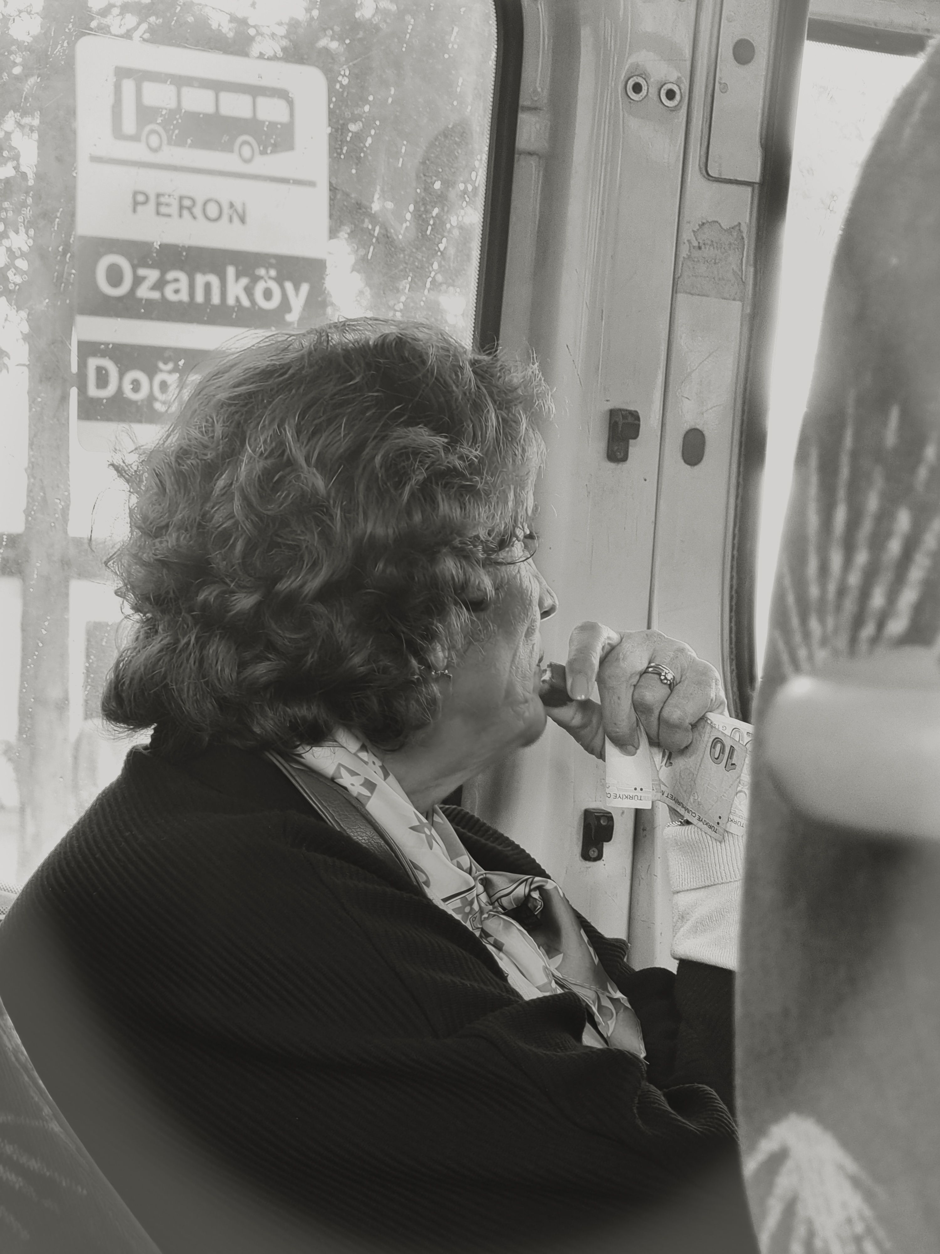 Elderly woman looking out the window during a thoughtful bus ride in Ozanköy.