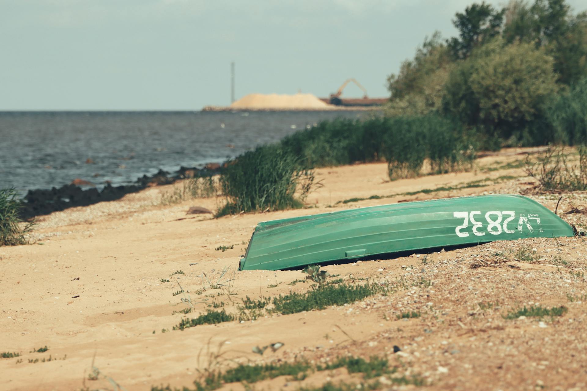 Tranquil Baltic beach scene with an inverted boat on sandy shore in Saulkrasti, Latvia.