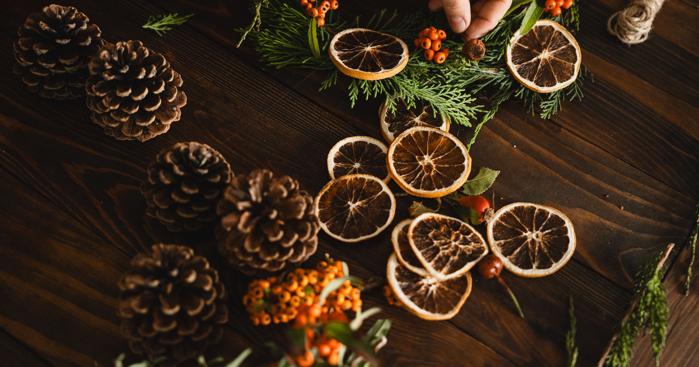 diy-christmas-decor Handmade Christmas garland of dried orange slices, pinecones and berries on a wooden table