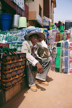 A vendor sits among colorful bags and baskets at a bustling market in Lagos, Nigeria.