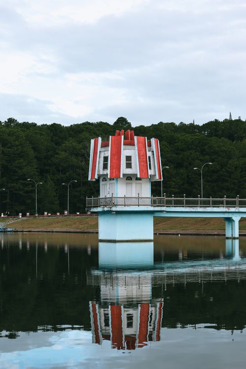 Free Scenic view of red-roofed structure on Tuyen Lam Lake in Da Lat, Vietnam with reflection in water. Stock Photo
