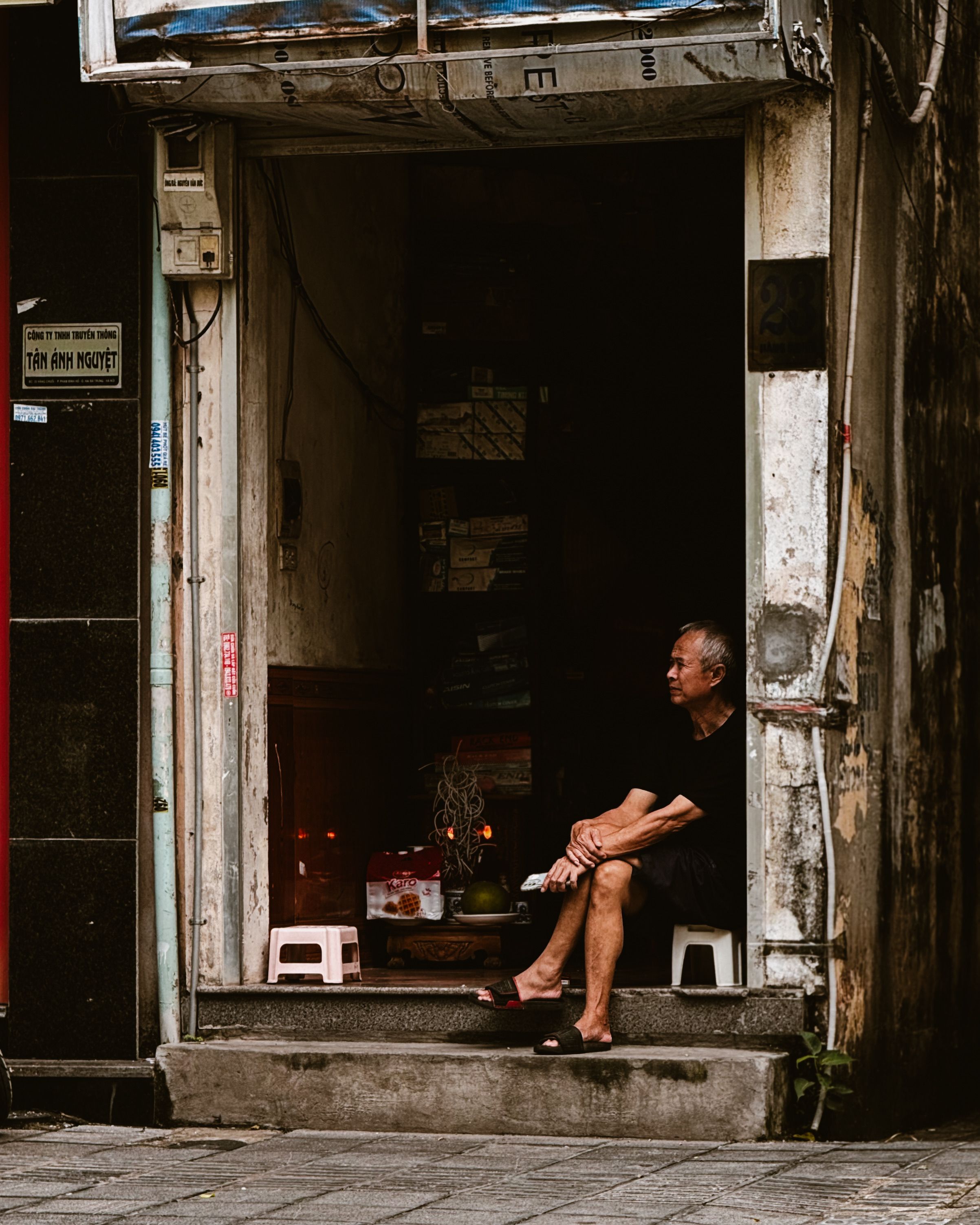 An elderly man sitting in a doorway, offering a glimpse into daily life in Hanoi, Vietnam.
