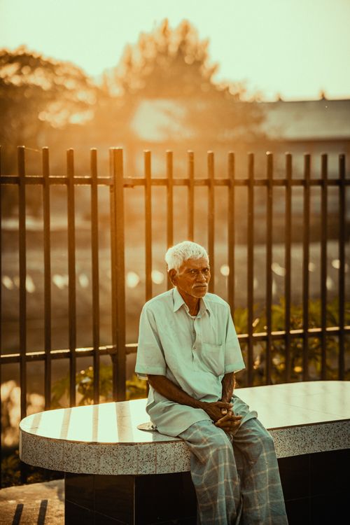 Free Elderly man sitting on a bench at sunset in Feni, Bangladesh, exuding tranquility. Stock Photo
