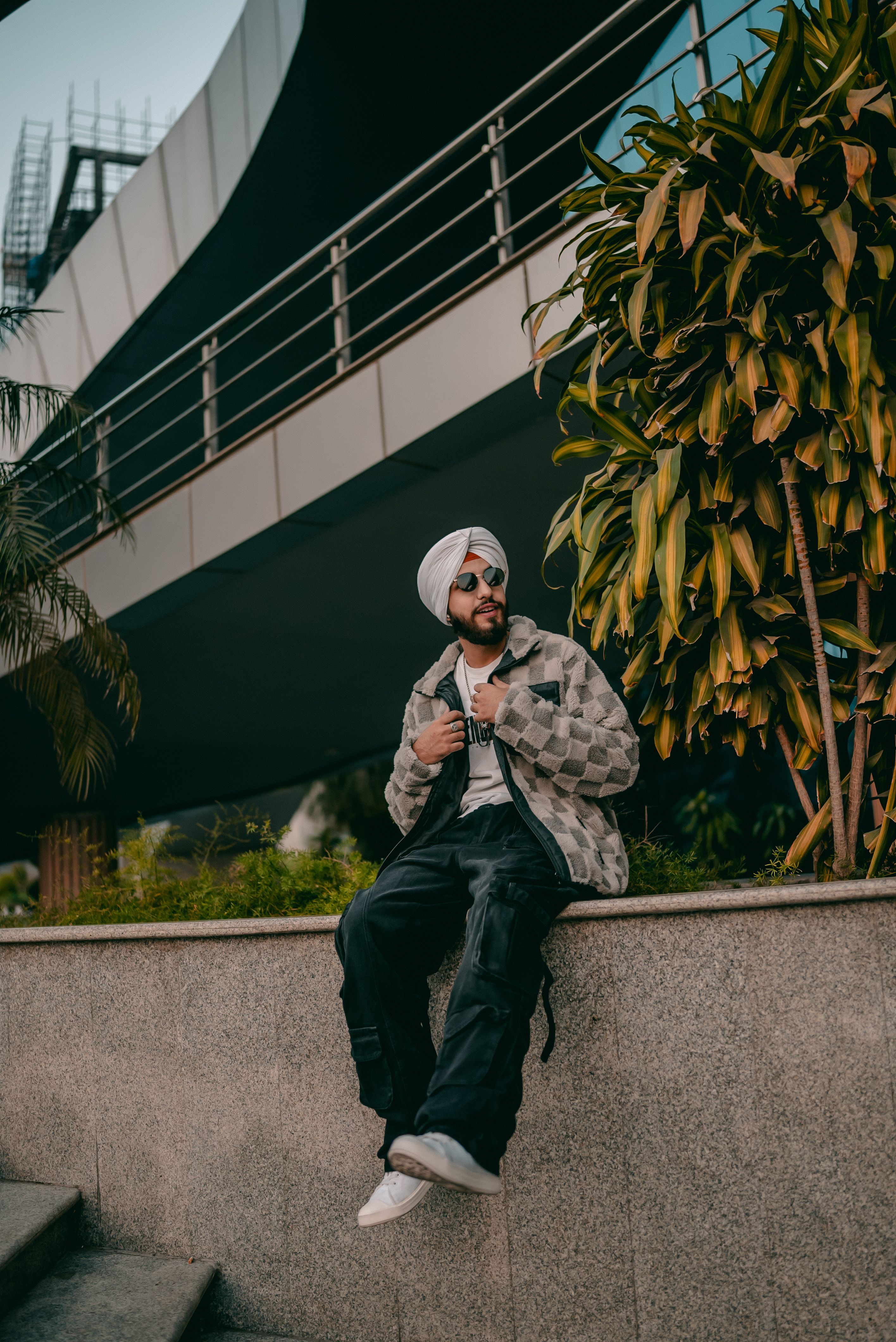 Turbaned man exudes style sitting on a ledge in an urban environment
