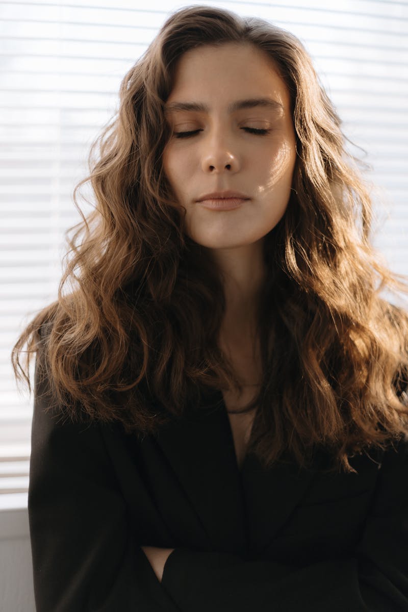 Serene woman with closed eyes in soft morning light, peaceful aftermath of deep surrender and connection