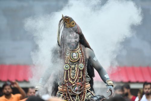 Free A traditional male performer dressed in cultural attire at a festival, surrounded by smoke. Stock Photo
