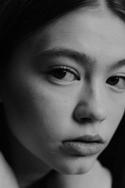 Black and white close-up portrait capturing a thoughtful young woman.
