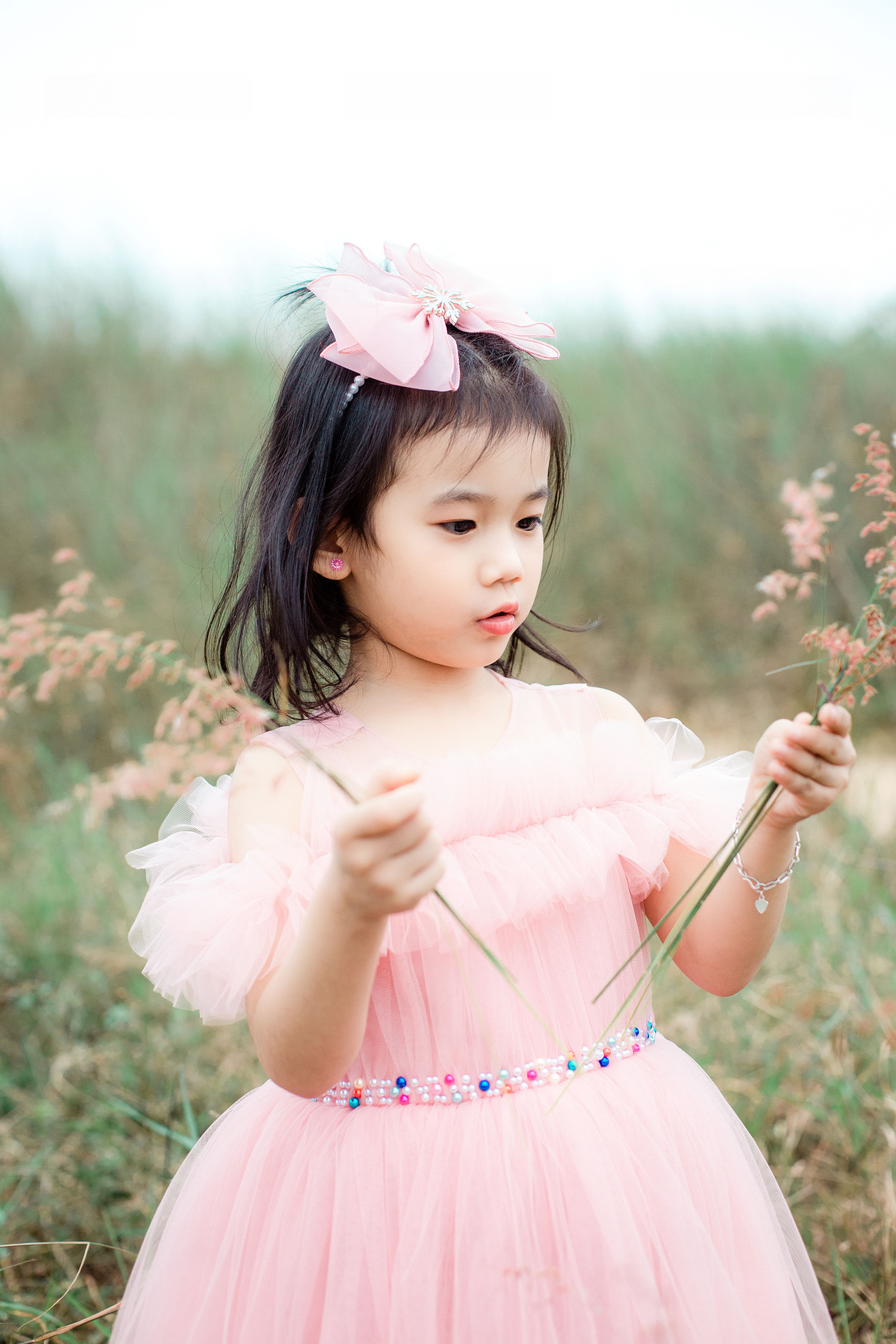 Young Girl in Pink Dress Holding Flowers Outdoors · Free Stock Photo