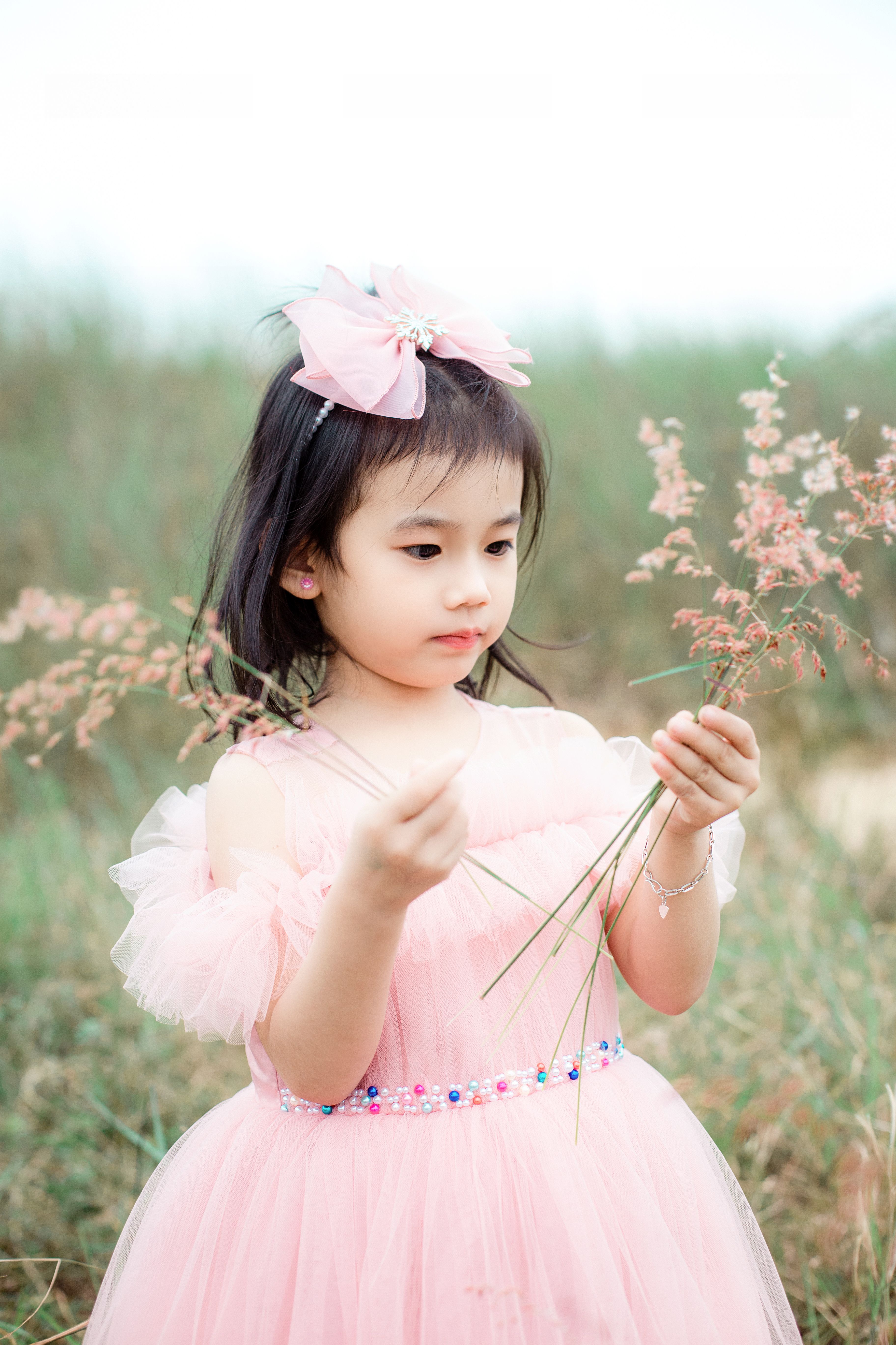 Little Girl in Pink Dress Holding Flowers in Field · Free Stock Photo
