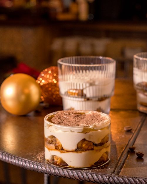 Free Delicious tiramisu with Christmas decorations in a cozy café atmosphere, perfect for holiday treats. Stock Photo