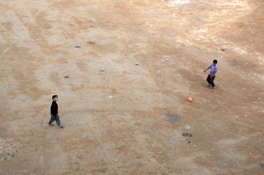 Two children playing soccer on a dirt field in Sefrou, Morocco.