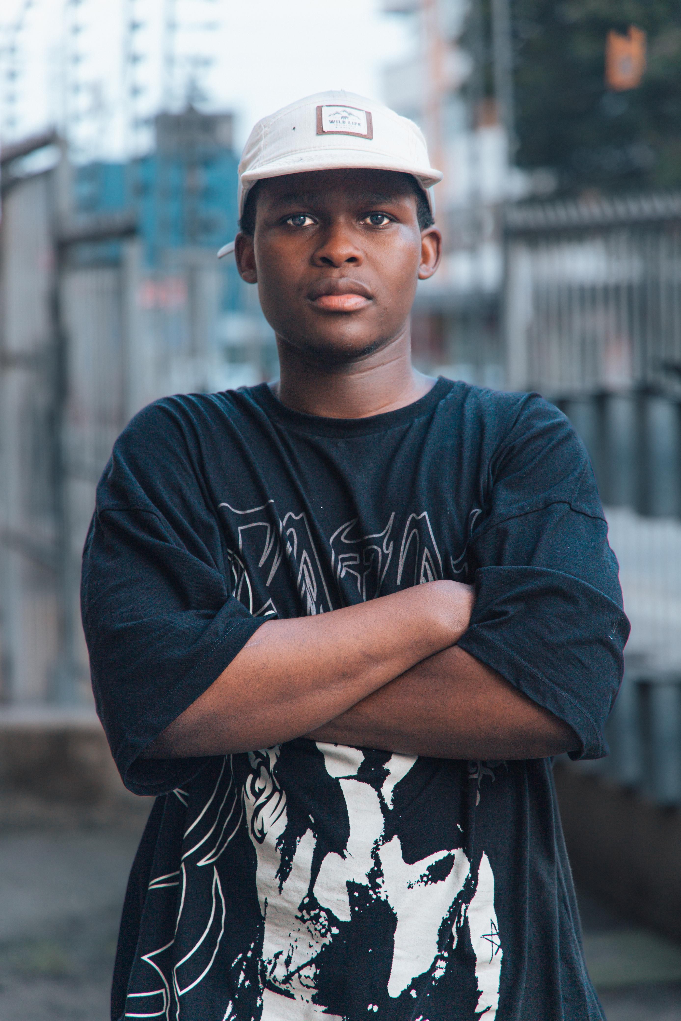 A confident young man with crossed arms in an urban setting.