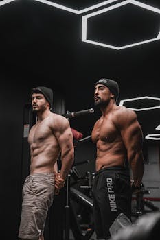 Two muscular men posing under unique geometric lights in a modern gym.