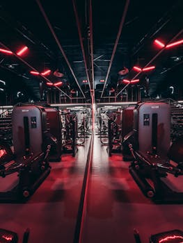 Fitness center with sleek gym equipment and red neon lights creating a futuristic ambiance.