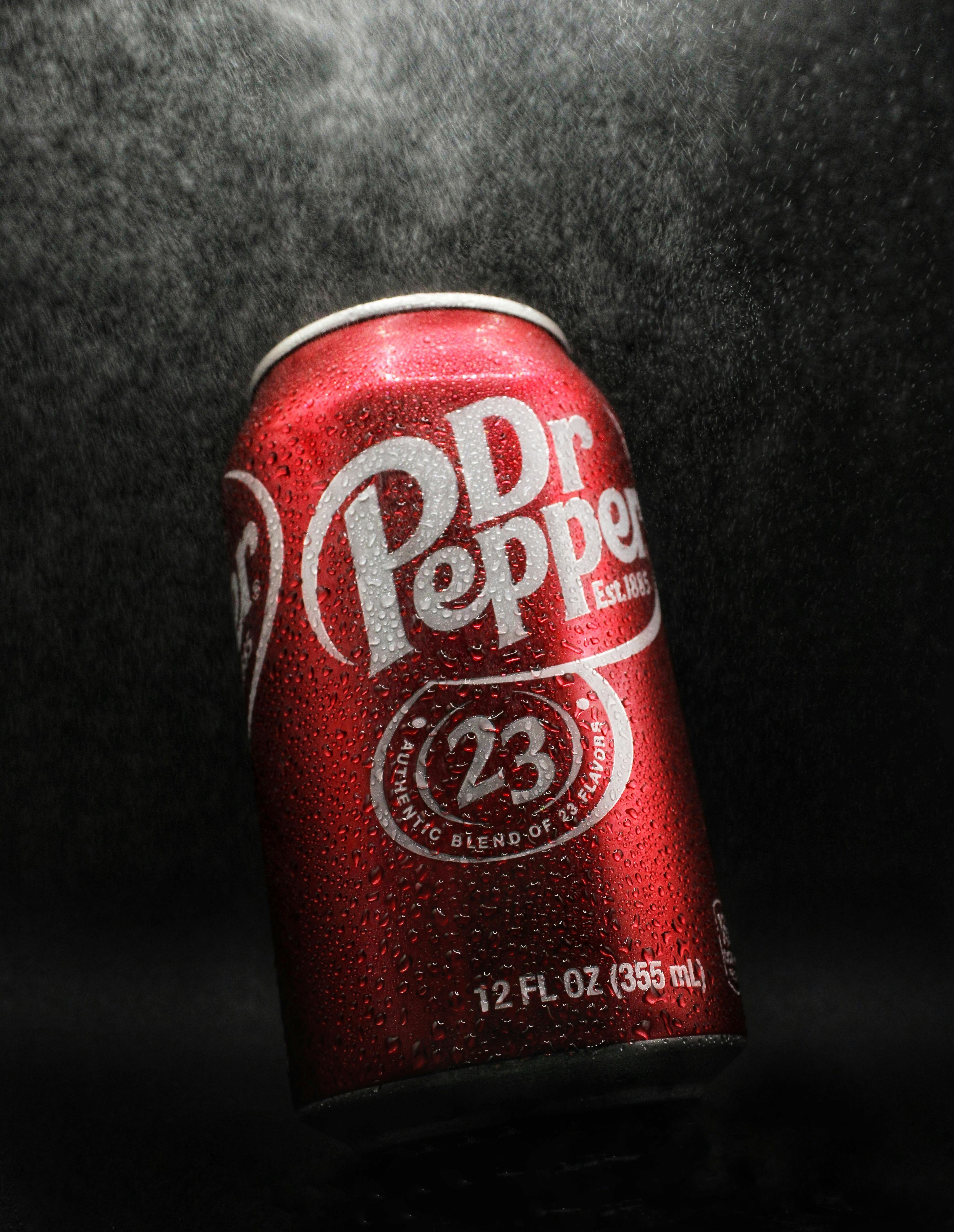 Close-up of a cold Dr Pepper can covered in water droplets against a dark background.