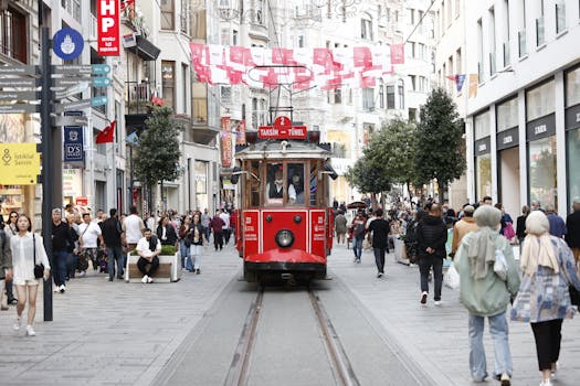 Vibrant street scene on İstiklal Avenue featuring the iconic red tram and bustling crowd.