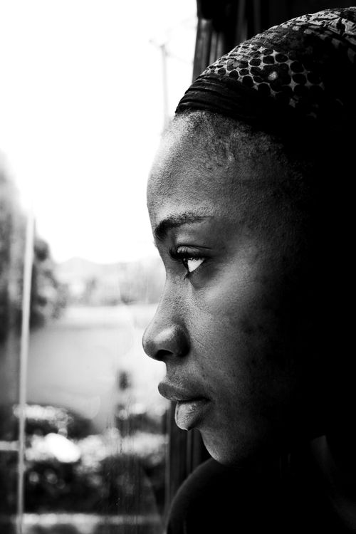 Free Black and white profile portrait of a thoughtful woman looking out a window in Abuja, Nigeria. Stock Photo