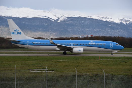 KLM Boeing 737 preparing for takeoff at Geneva Airport with snowy Jura Mountain backdrop.