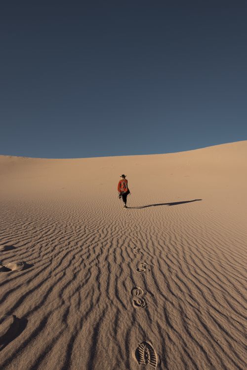 Free A person walks on sand dunes under a clear sky, USA desert landscape. Stock Photo