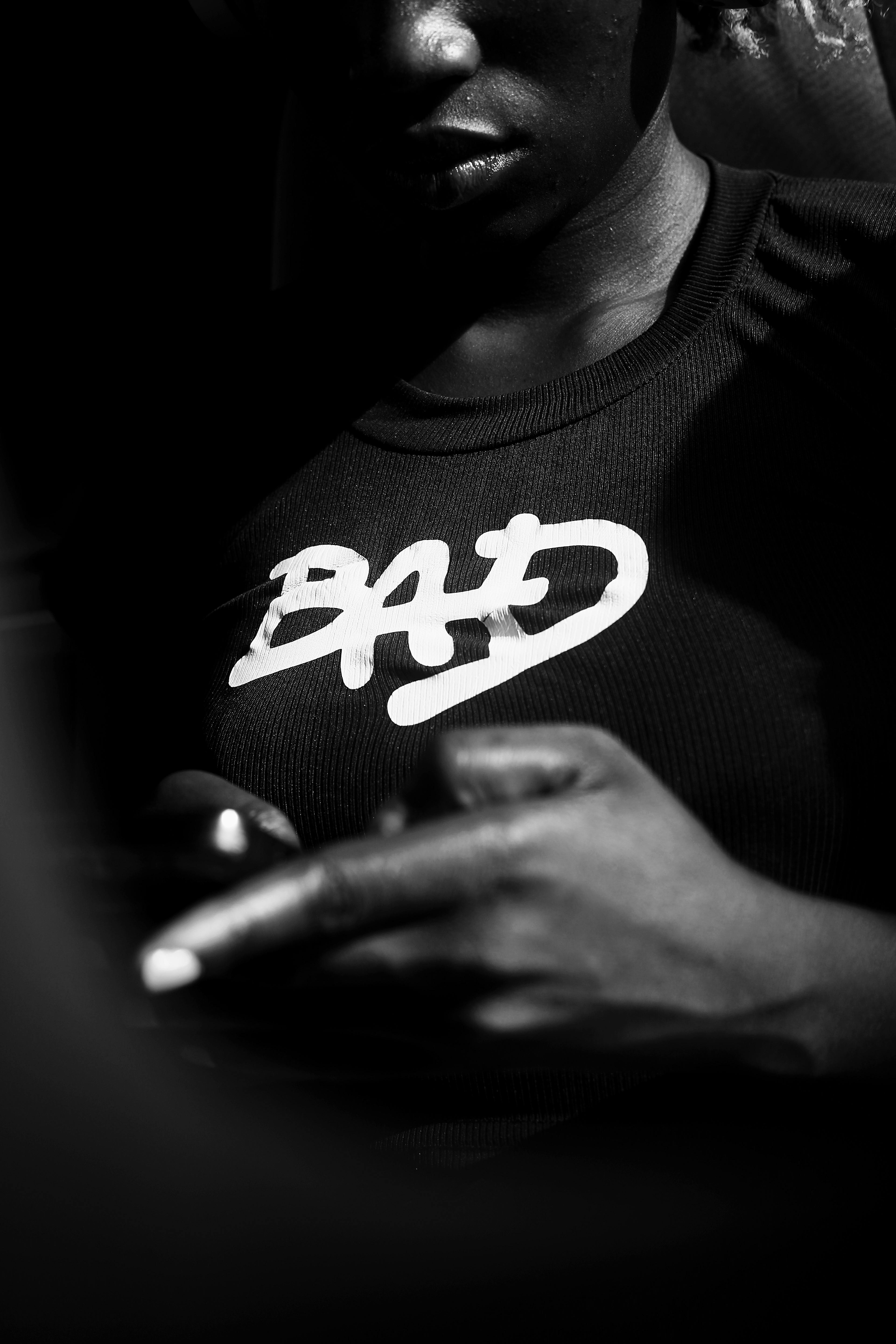 Gratis Dramático retrato en blanco y negro de una persona que viste una camiseta con la frase "BAD", tomado en Abuja, Nigeria. Foto de stock