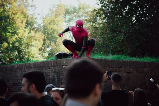 Spider-Man cosplayer posing for photos at an outdoor event, attracting a lively crowd.