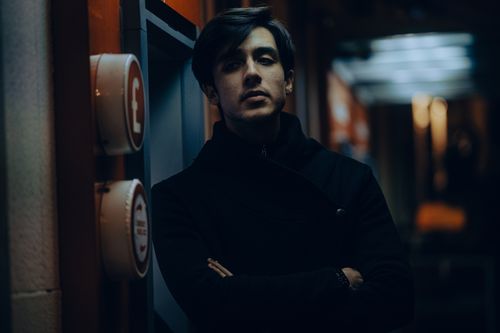 Free Introspective young man standing in dimly lit urban setting at night. Stock Photo