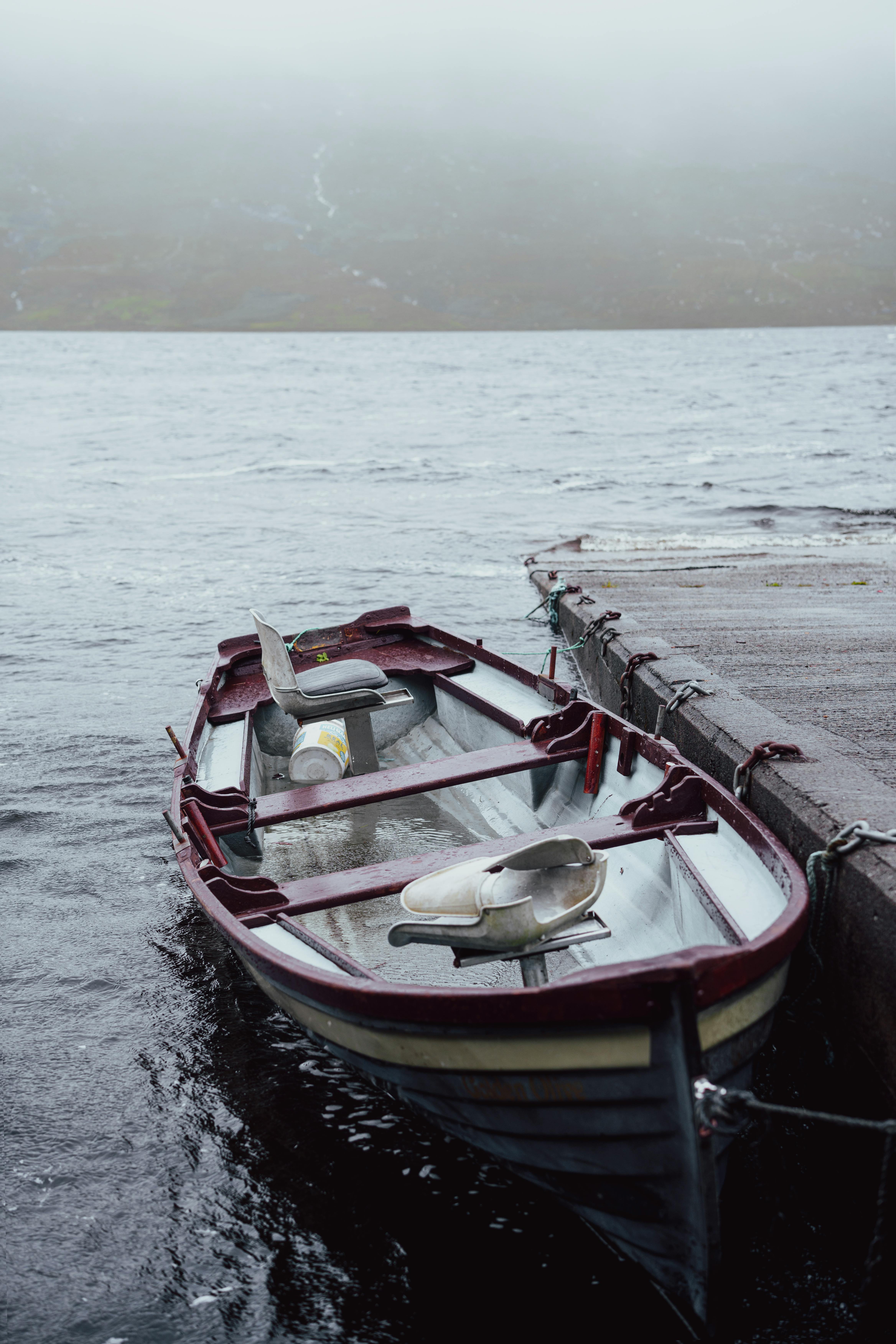 A solitary rowboat tied to a pier on a foggy lake, creating a serene and introspective mood.