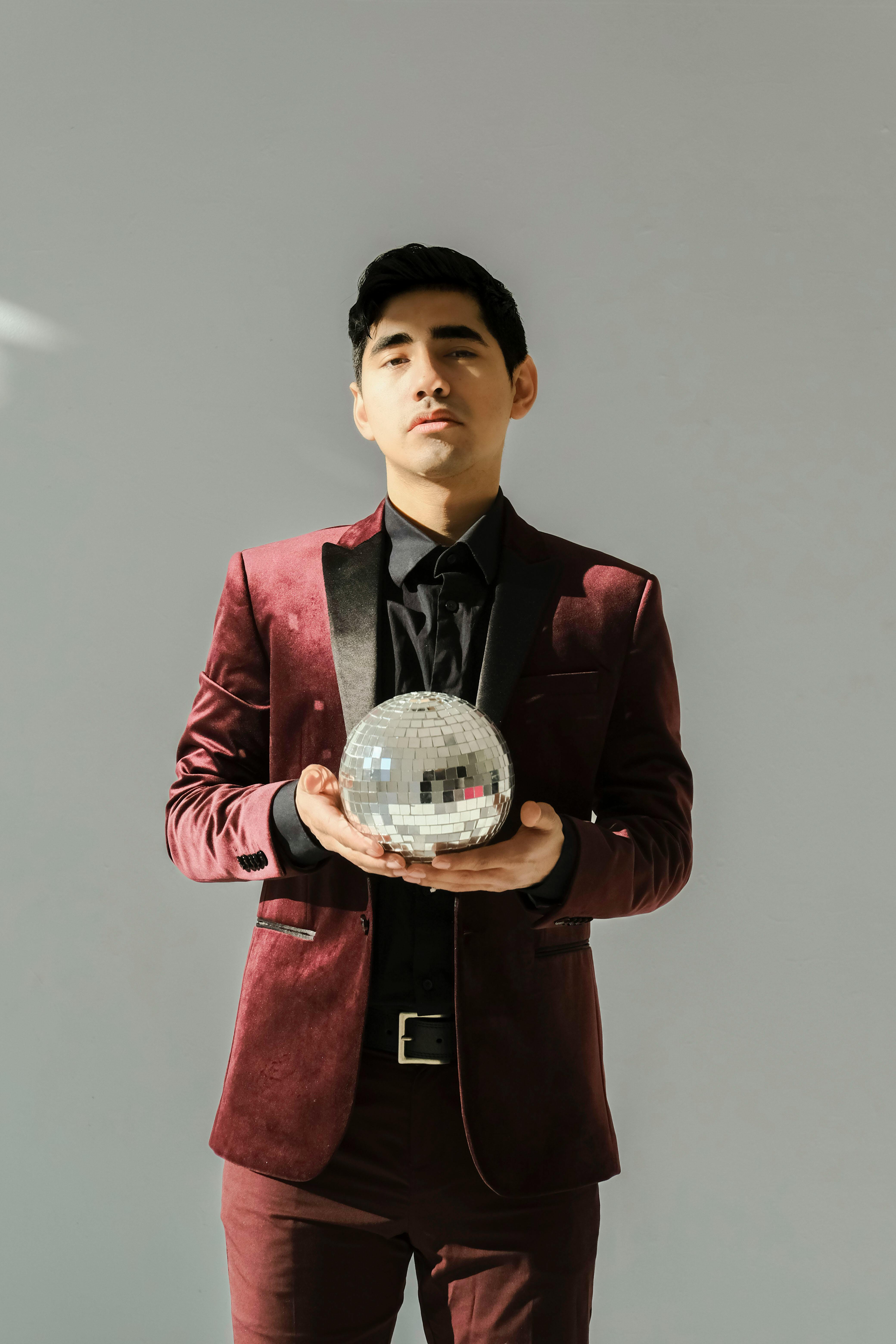 stylish man holding disco ball in studio