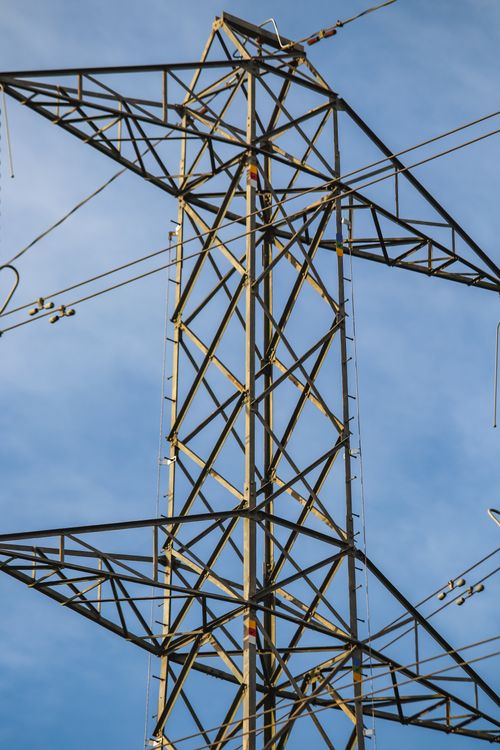 Free Detailed view of a high voltage transmission tower structure against a blue sky. Stock Photo