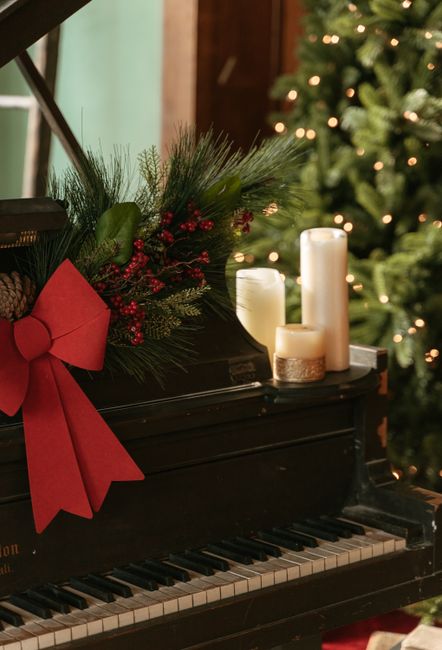 Black piano adorned with Christmas decor and candles, creating a festive holiday atmosphere.