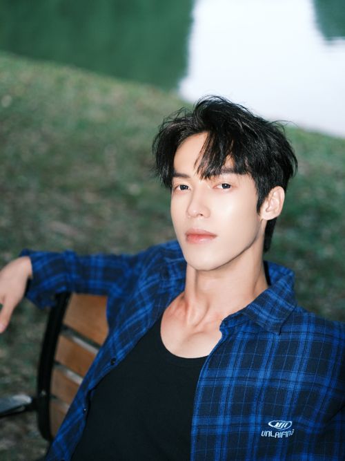 Free A young man in casual attire relaxes on a bench outdoors, exuding a confident and casual vibe. Stock Photo