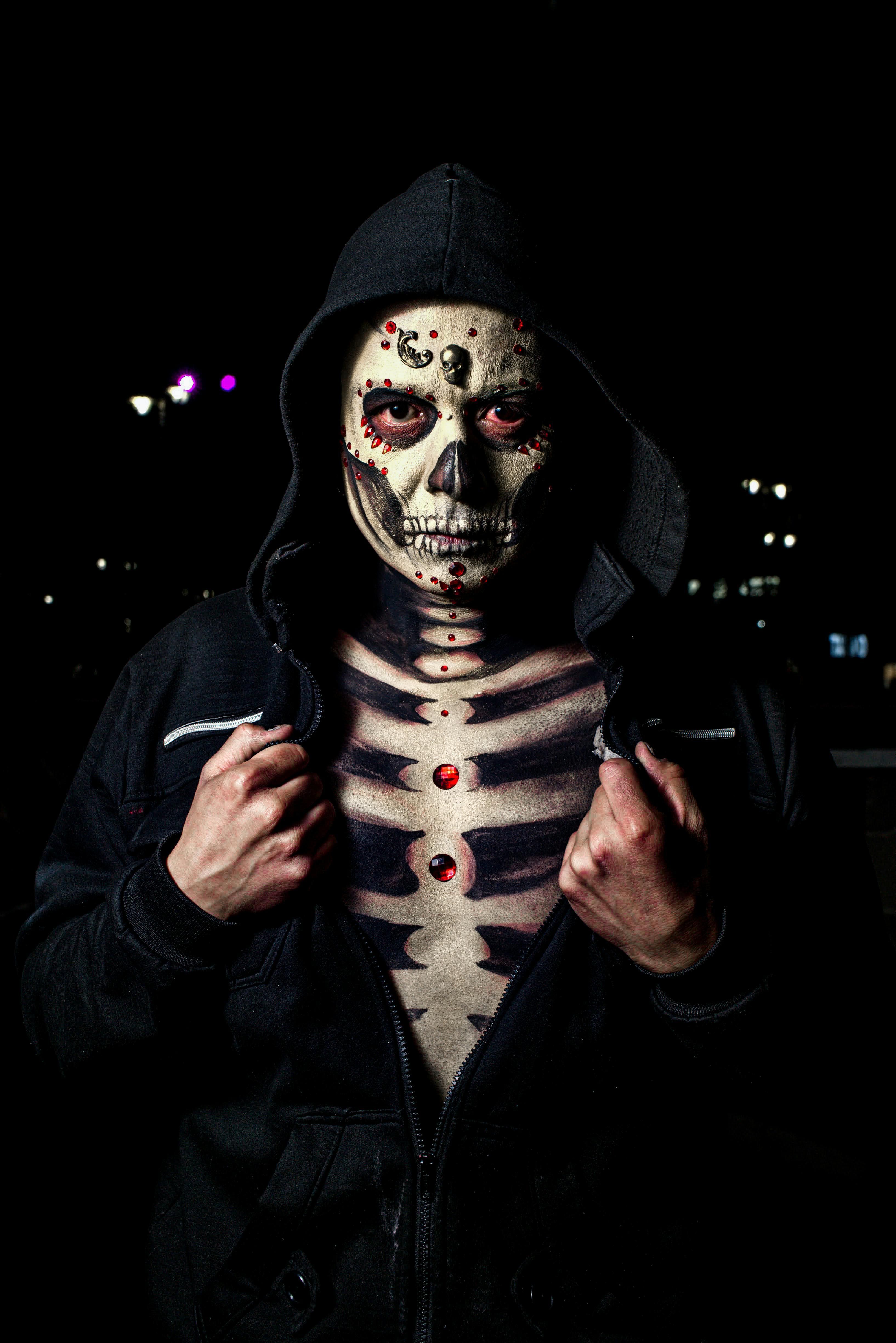 Ücretsiz Kapşonlu bir figürün iskelet vücut boyası ve süslemeleriyle dramatik gece portresi. Stok Fotoğraflar