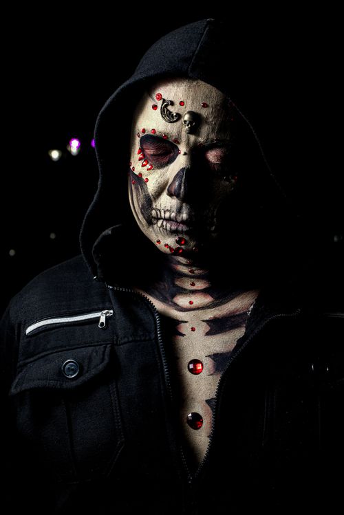 Free Spooky image of a person with a painted skull face wearing a hooded jacket at night. Stock Photo