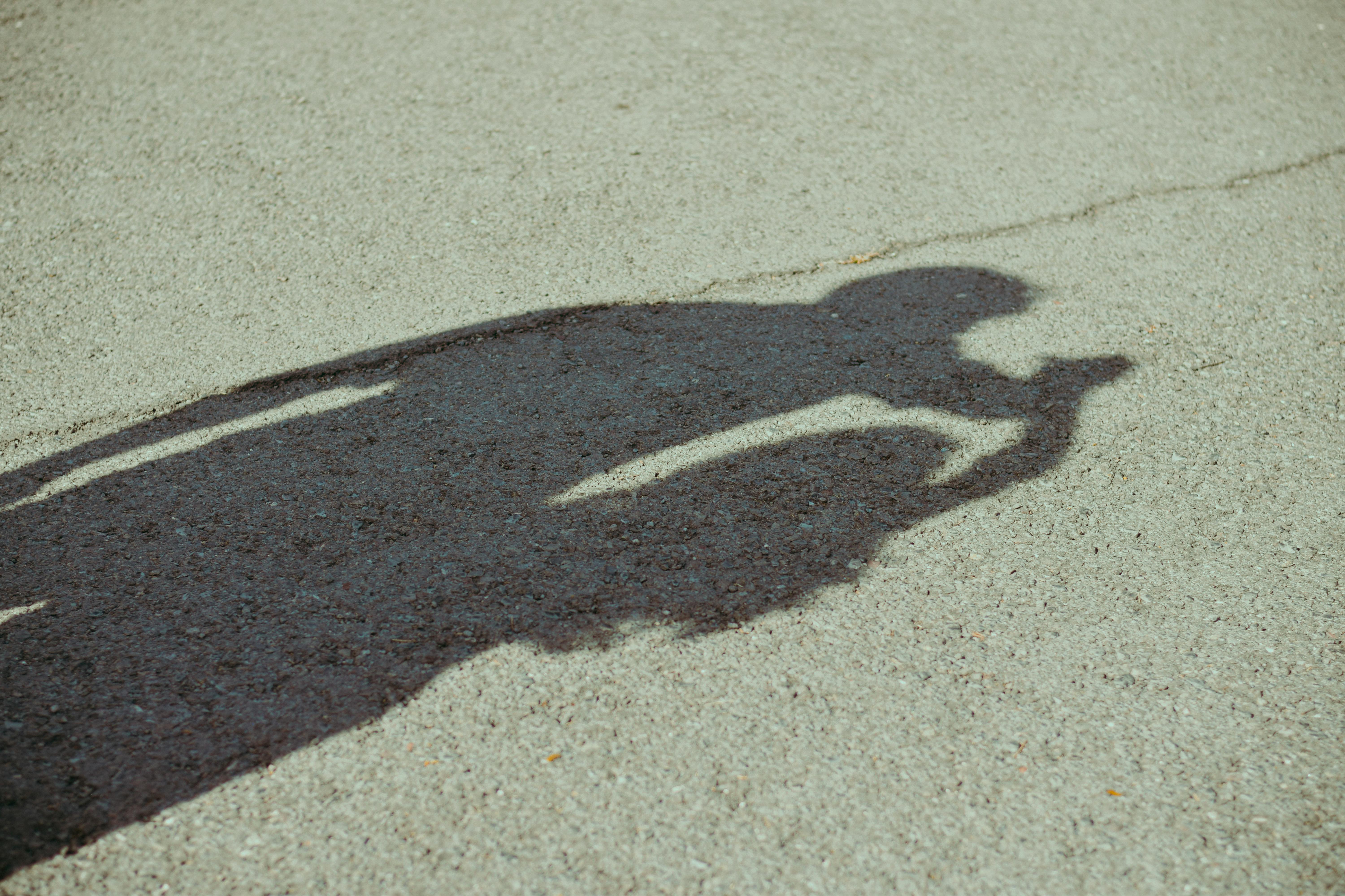 Kostenlos Der Schatten einer Person, die eine Kamera hält, wird auf einer Bürgersteigoberfläche reflektiert. Stock-Foto