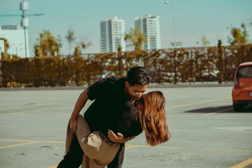 Free A couple enjoying a romantic moment together outdoors in a city parking lot on a sunny day. Stock Photo