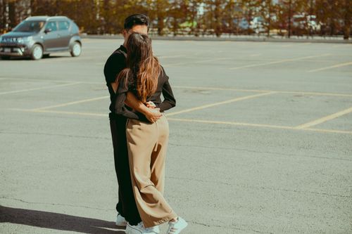 Free A couple warmly embrace in a sunlit empty parking lot, expressing love. Stock Photo