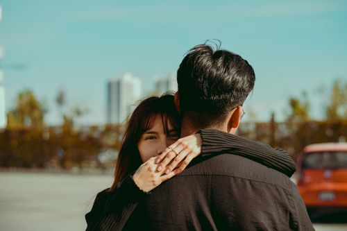 Free Young couple embracing with city skyline in the background. Emotional and romantic outdoor scene. Stock Photo
