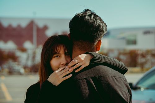Free A tender embrace shared by a young couple under the bright sunlight in an outdoor setting. Stock Photo