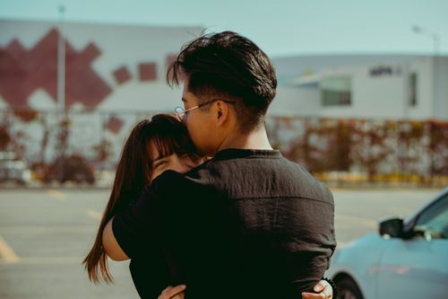 Free A young couple shares a heartfelt embrace outdoors on a sunny day, showcasing warmth and affection. Stock Photo