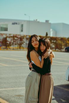 Two young women embracing in an outdoor setting, symbolizing friendship and warmth.